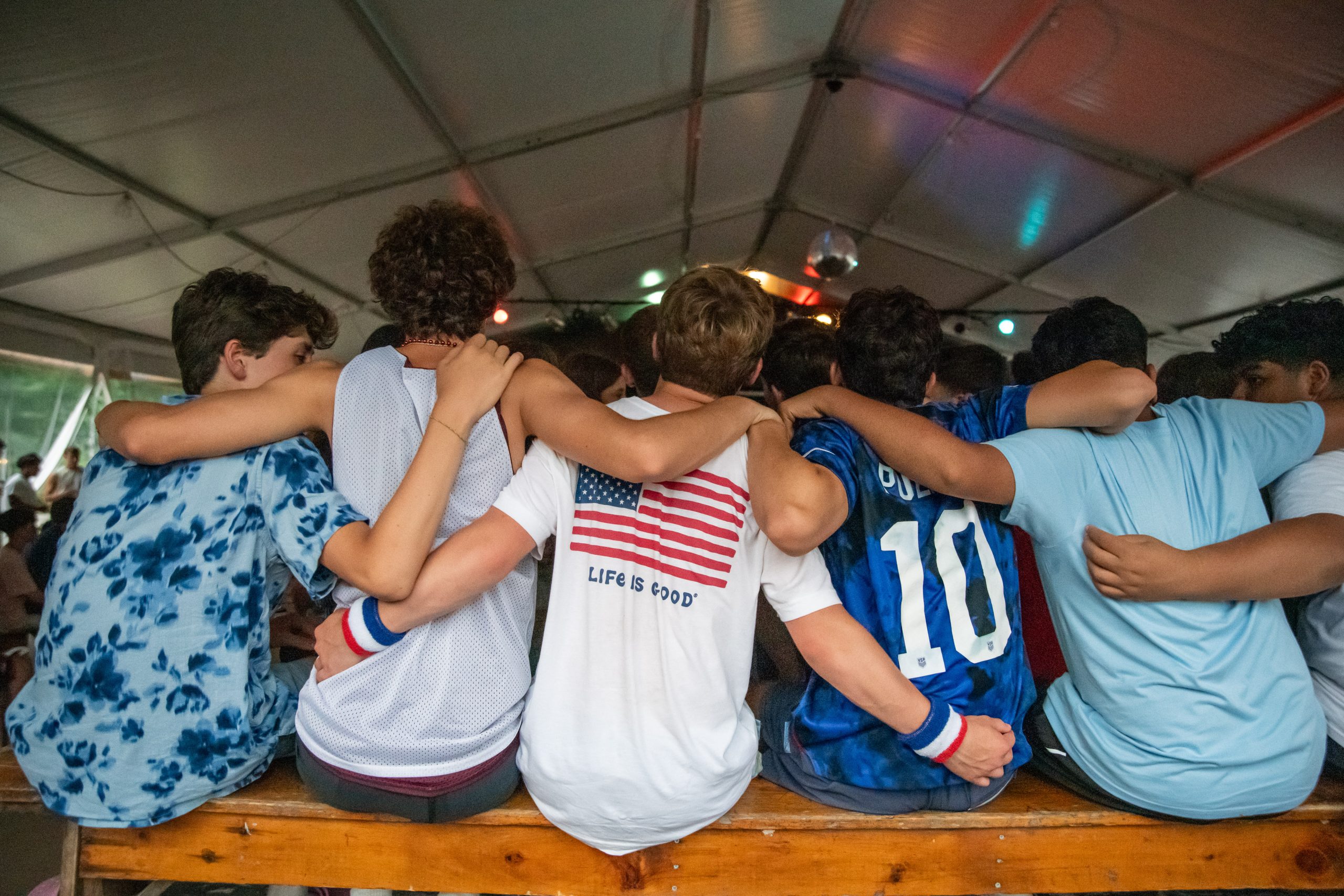 A row of campers, seen from behind, with their arms around each other