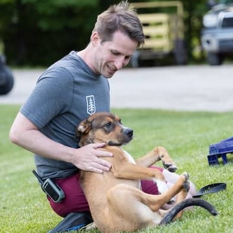 Jack Schott on the grass at camp with his dog Buster in his lap